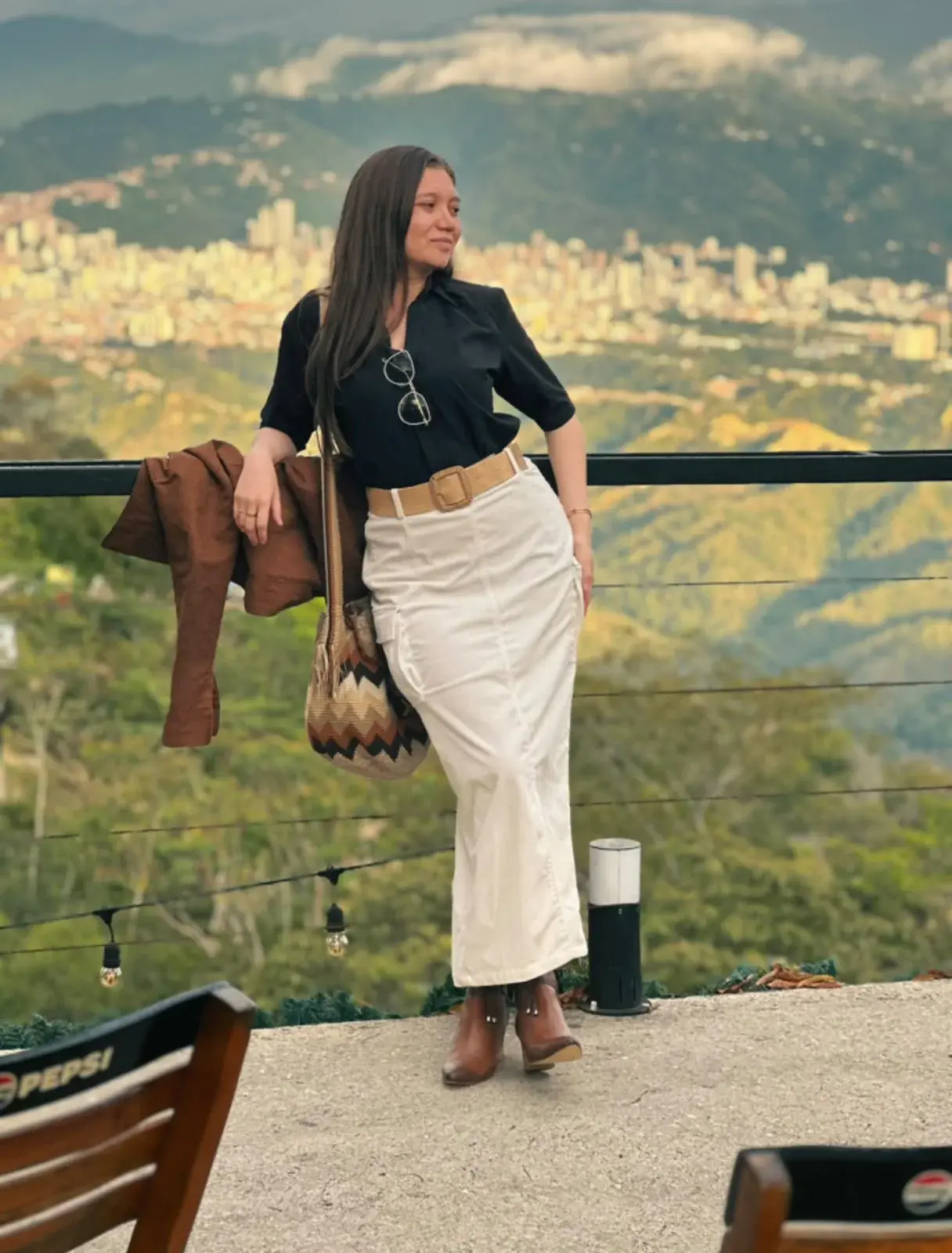 Ángela Giraldo con un look negro, marfil y camel frente a la ciudad